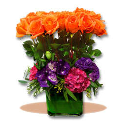 Orange roses and purple flowers in a green glass vase