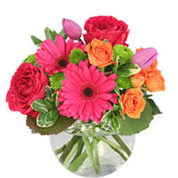 Bright mixed bouquet of pink and orange flowers in a clear vase