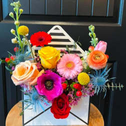 Colorful mixed flower arrangement in a white box with roses and gerbera daisies