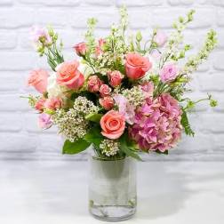 Pink and peach roses with hydrangea in a clear glass vase
