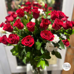 Arrangement of red roses with a few white blooms in a clear glass vase