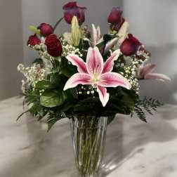 Pink lilies and red roses in a clear glass vase