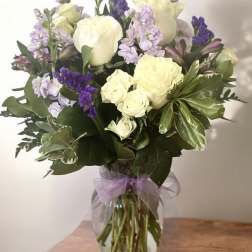 Bouquet of white roses and purple flowers in a glass vase