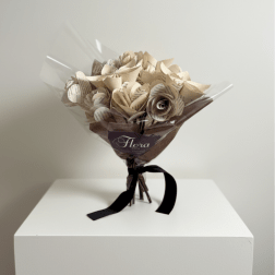 Bouquet of cream paper roses made from printed pages, wrapped in cellophane with brown paper and a black ribbon.