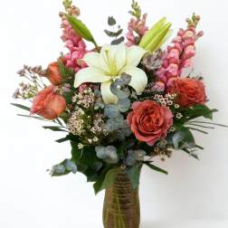 Bouquet of lilies, roses, and pink snapdragons in a glass vase