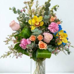 Mixed bouquet of roses, orchids, and carnations in a glass vase