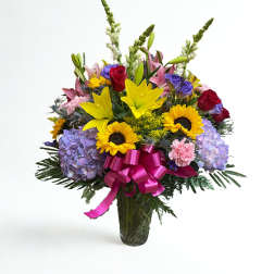 Mixed bouquet of lilies, roses, sunflowers, and hydrangeas in a glass vase