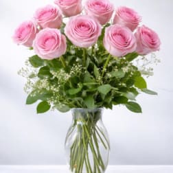 Arrangement of pink roses with white filler flowers in a clear glass vase