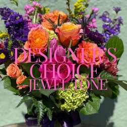 Bright jewel-tone bouquet with orange and pink roses, purple blooms, and green hydrangea.