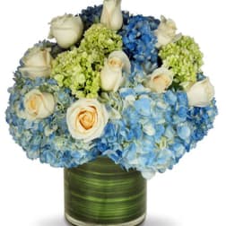Blue hydrangeas and white roses arranged in a green glass vase