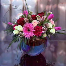 Mixed pink and red bouquet in a round glass vase