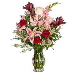 Mixed bouquet of pink and red flowers in a clear glass vase