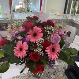 Mixed bouquet of pink gerbera daisies and red roses in a glass vase