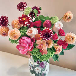 Colorful bouquet of dahlias, roses, and orchids in a decorative vase