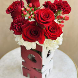 Red roses and carnations arranged in a decorative box