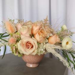 Peach roses and white ranunculus in a pink vase