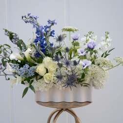 Blue, white, and cream floral arrangement in a white container