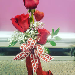 Red roses arranged with baby's breath and a heart decoration in a glittery high-heel vase
