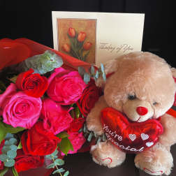 Bouquet of red and pink roses with a teddy bear holding a heart
