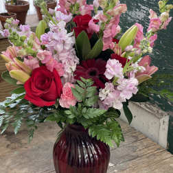Mixed pink and red flower arrangement in a burgundy vase