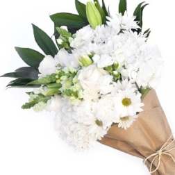White bouquet with daisies and lilies wrapped in brown paper