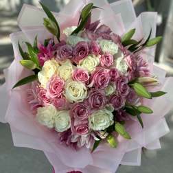 Bouquet of pink and white roses with lily buds wrapped in pale pink paper