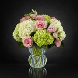 Pink roses and green hydrangeas in a clear glass vase