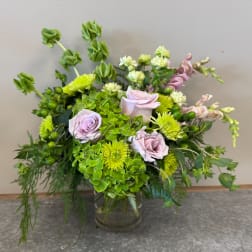Mixed bouquet of lavender roses, green chrysanthemums, and hydrangea in a glass vase