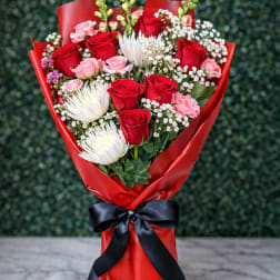 Bouquet of red and pink roses with white blooms wrapped in red paper