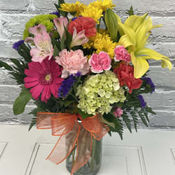 Colorful mixed bouquet in a glass vase with an orange ribbon