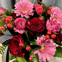 Bouquet of pink gerbera daisies and red roses with striped ribbon