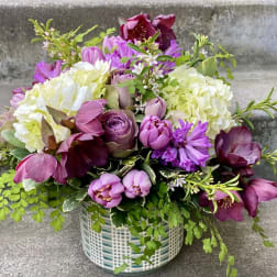 Purple and white floral arrangement in a patterned ceramic vase