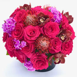 Hot pink roses with purple orchids in a black vase