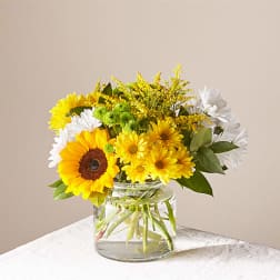 Yellow and white flowers arranged in a clear glass vase