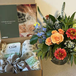 Gift box with flowers, a cocktail kit, and accessories beside a colorful bouquet