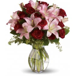 Red roses and pink lilies arranged in a clear glass vase