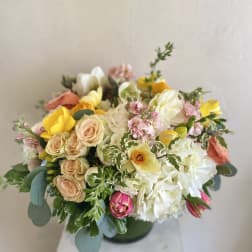 Mixed bouquet of pastel roses, tulips, and white blooms in a vase