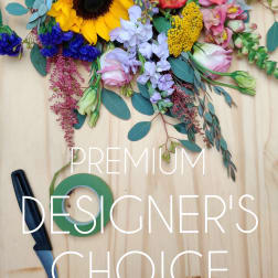 Mixed bouquet with sunflower, roses, and pastel blooms on a wooden surface