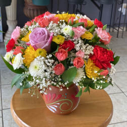 Mixed bouquet of roses, carnations, and chrysanthemums in a painted ceramic vase