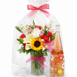 Mixed flower bouquet in a glass vase beside a bottle of rosé
