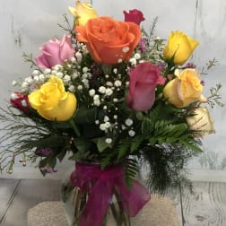 Colorful rose bouquet in a glass vase with a magenta ribbon