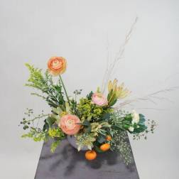 Low floral arrangement with peach blooms in a gray container