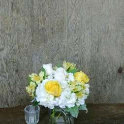 Yellow and white roses in a square glass vase with white hydrangeas