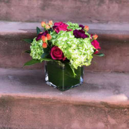Pink roses and green hydrangeas in a square glass vase