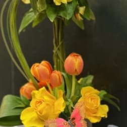 Yellow and orange floral arrangement in a square container with butterfly accents
