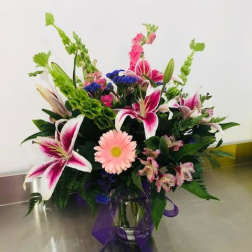 Mixed bouquet in a glass vase with pink lilies and a pink daisy