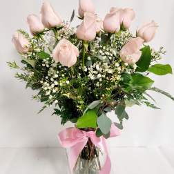 Pink roses in a glass vase with baby's breath and a pink ribbon
