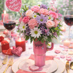 Pink floral arrangement in a mug with Mother's Day picks