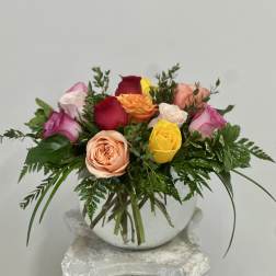 Mixed roses arranged in a round white vase