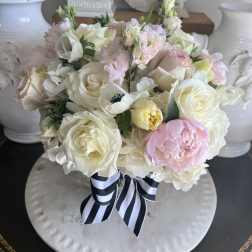Pastel bouquet of roses, peonies, and white blooms tied with a striped ribbon